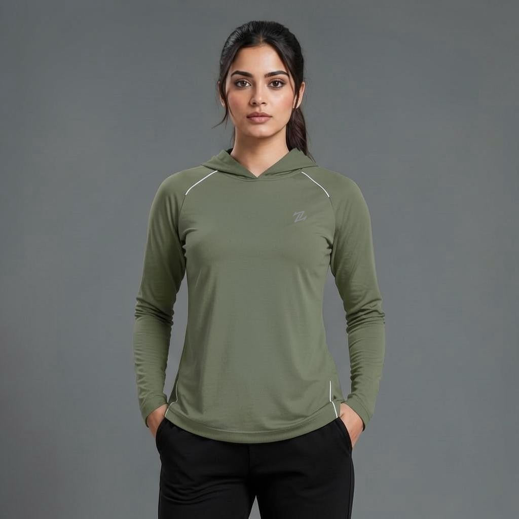 A woman modeling an olive green long-sleeve athletic hoodie with white piping details and a small logo on the left chest, paired with black pants, against a solid gray studio background.